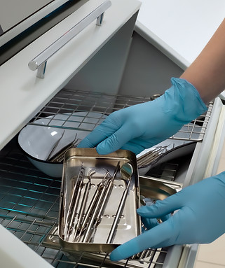 Close up dentist taking set dental instruments from sterilizer