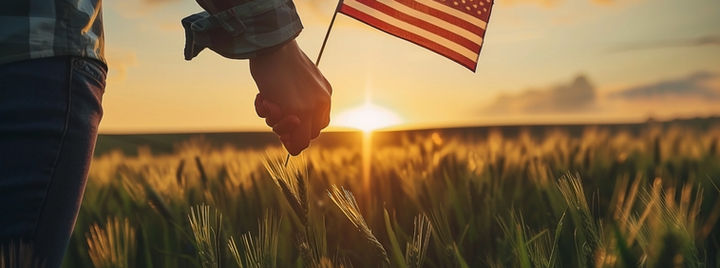 closeup-hands-holding-american-flag-wheat-field-sunset.jpg