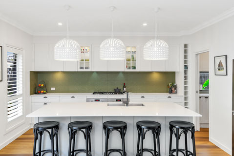 Modern kitchen with white island, black stools, and pendant lights