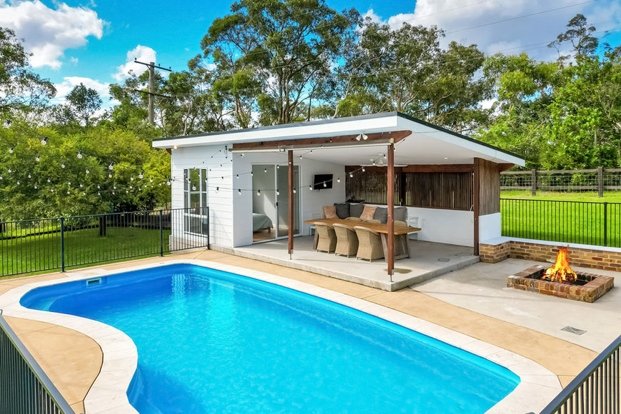 Backyard with swimming pool, modern pool house, and fire pit