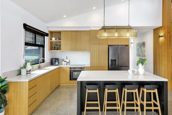Modern kitchen with wood cabinets, white counters, black island