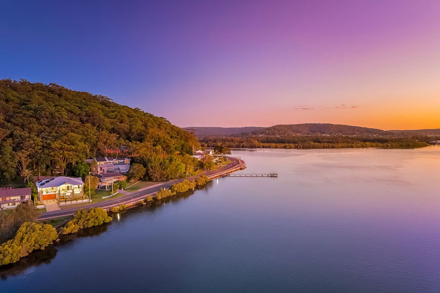Colorful sunset over a lake, homes, and forested hill
