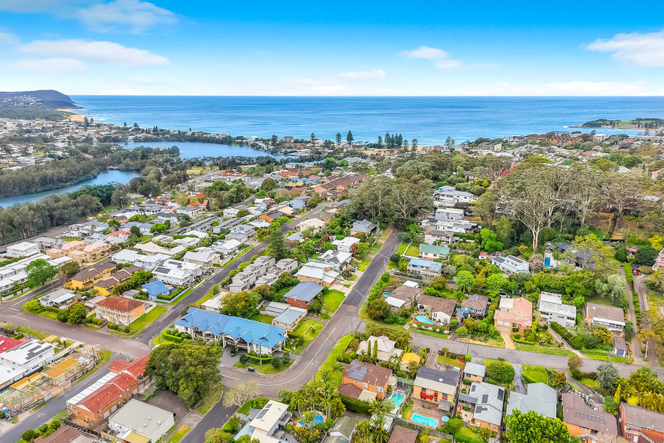 Aerial view of a coastal town with houses, a lake, and ocean.