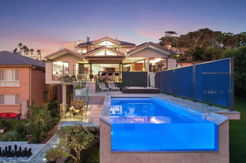 Luxury home with elevated glass-sided pool at dusk