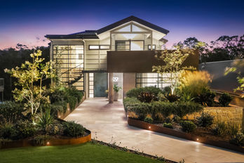 Modern house at dusk with illuminated landscaping