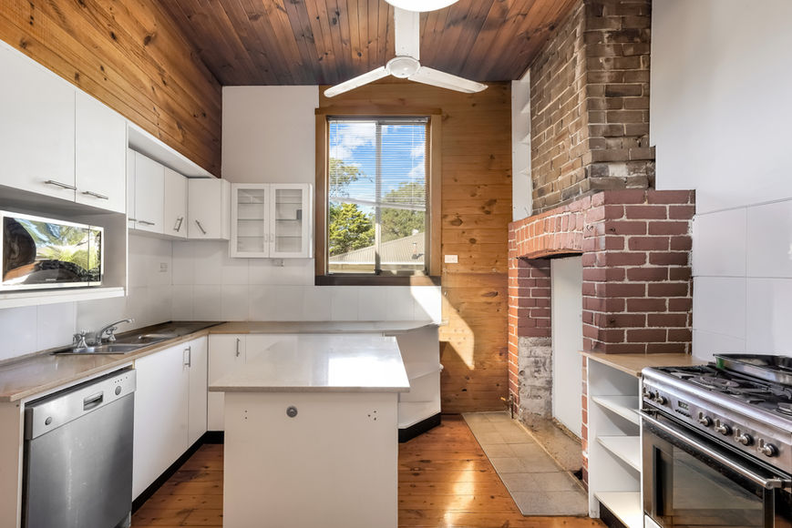 Kitchen with white cabinets, wood ceiling, and brick fireplace