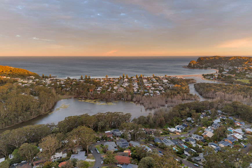 Aerial view of coastal town, houses, lake, and ocean at sunset
