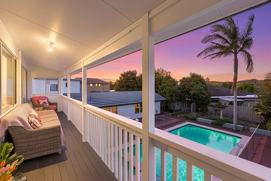 Balcony with seating overlooking a swimming pool at sunset