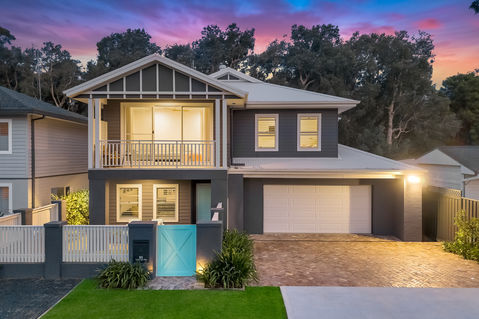 Modern house with grey exterior and turquoise gate at dusk