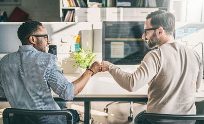 Two attendees at an Alpstra Five Behaviors training bumping hands