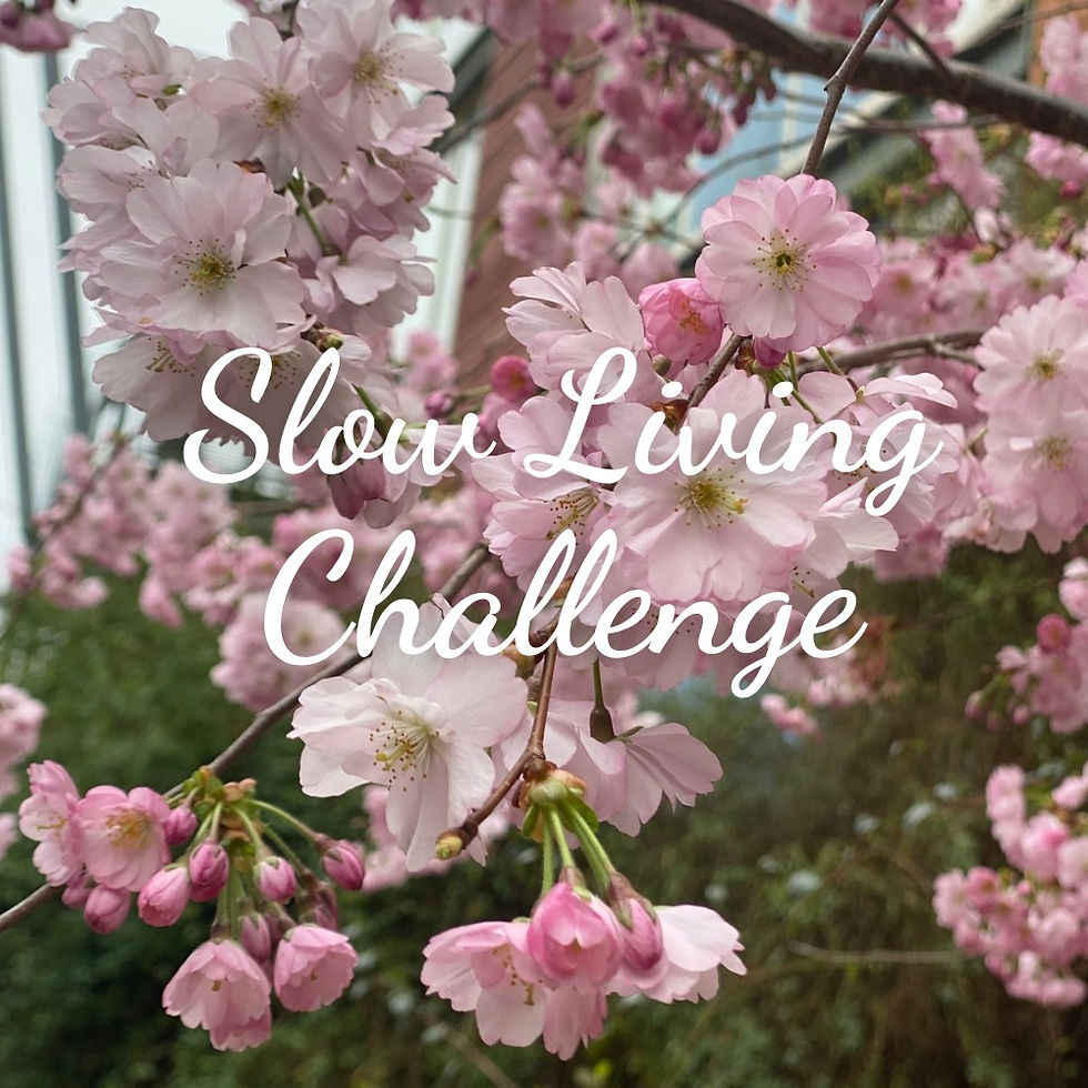 Pink cherry blossoms with "Slow Living Challenge" text overlay. Background shows green leaves, creating a serene and calm mood.