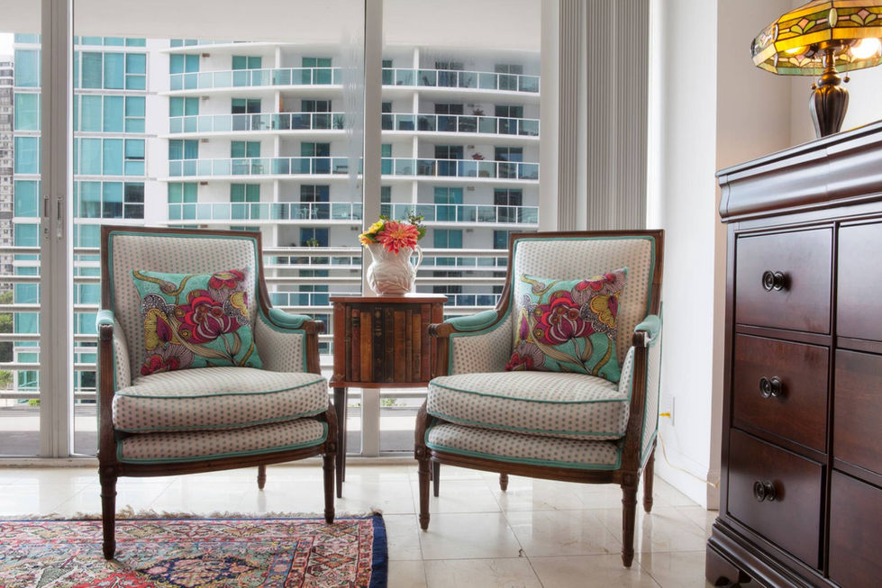 Modern seating nook with patterned chairs and city views, styled by a Miami interior designer for an urban residence
