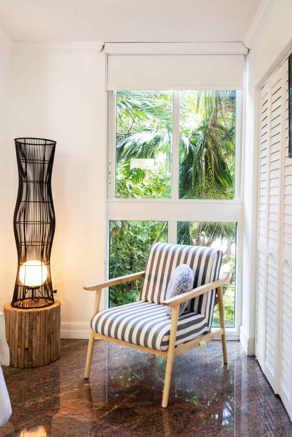 Miami coastal sitting nook with striped accent chair, sculptural floor lamp, tropical views, and modern interior design