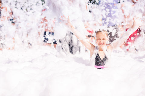 Foam Party on the beach. Cute little girl having fun and dancing..jpg