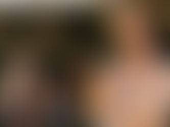 Blonde Frau lächelt selbstbewusst in die Kamera, im Hintergrund eine Familie beim Picknick in der Natur