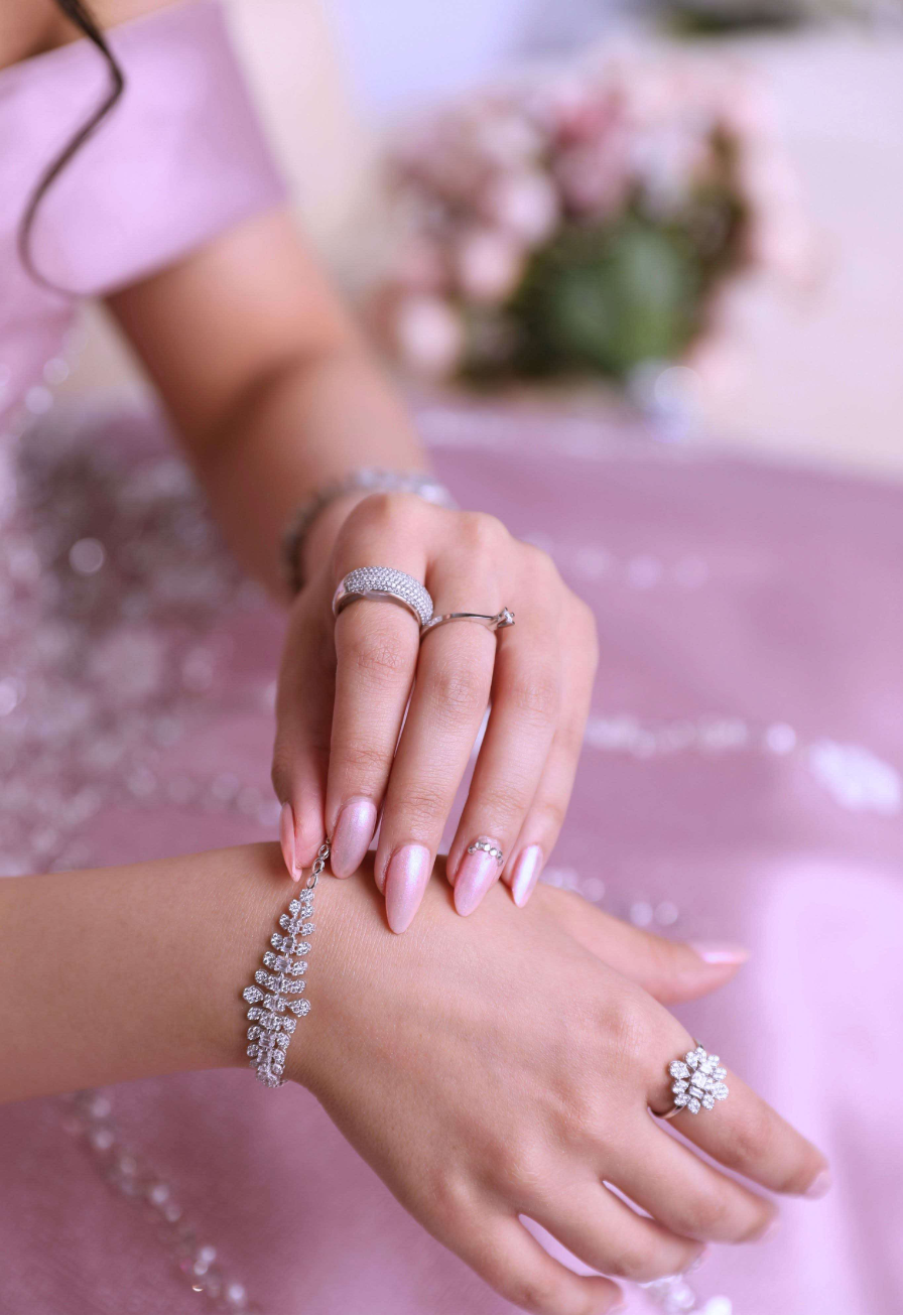 Rings and bracelets on a handmodel with light pink background