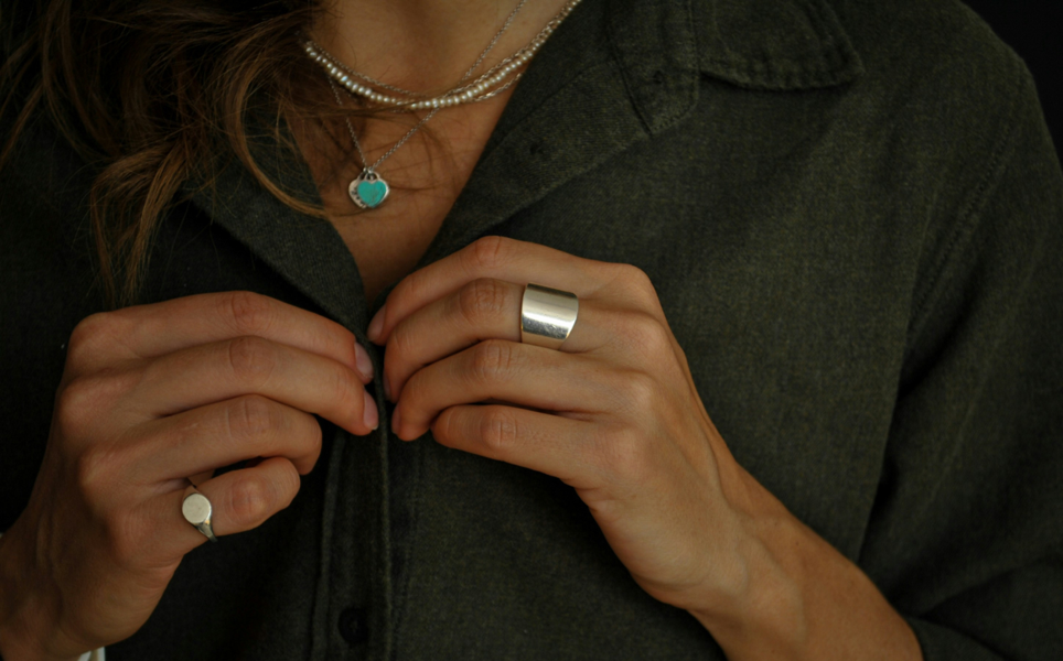 Woman with sustainable jewelry- green shirt, rings and necklaces