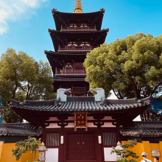 A Hanshan temple surrounded by trees under a bright blue sky.