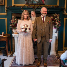 Wedding with bride and groom in large room with a painting behind them