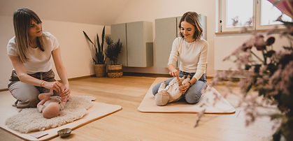 One woman shows another how to perform a baby massage.