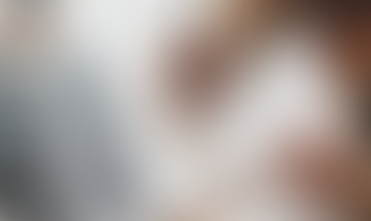 A woman sitting at a desk with a focused expression, holding a pen and poised to write on a blank notepad. A laptop, coffee mug, and office supplies surround her, suggesting she's preparing a checklist or action plan.