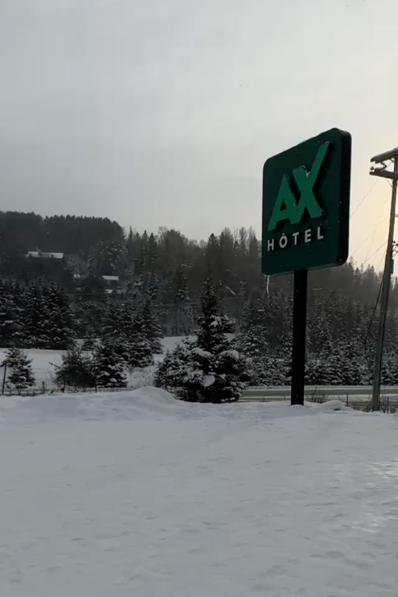 AX Hotel Mont-Tremblant sign surrounded by snowy trees in the Laurentian Mountains