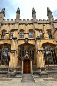 A towering Oxford University building with ornate stonework, large wooden doors, and gothic-style windows.