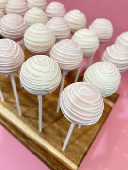 Pink and white swirl cake pops on wooden stand for girls birthday in Toronto