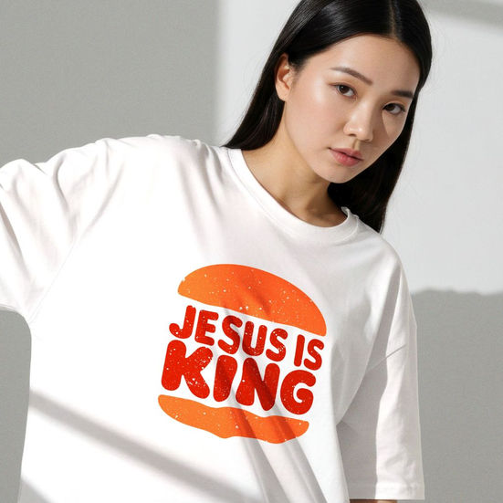 Woman wearing white Jesus Is King Christian graphic t-shirt with bold orange and red faith design