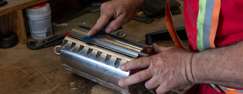Worker installing custom moulding knives into cutter head for wood moulding production