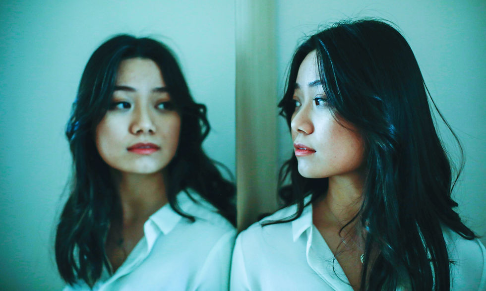Asian woman looking at herself in the mirror