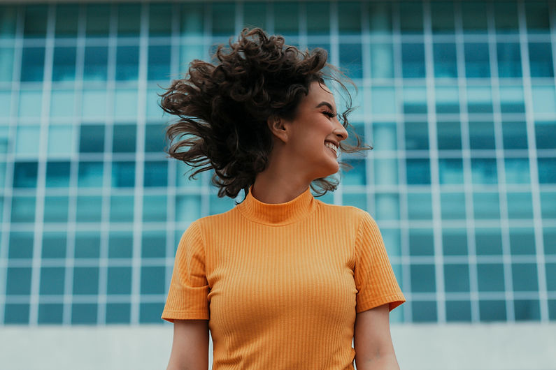 smiling woman in orange sweater agaist a blue background