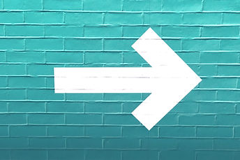 turquise wall with white painted arrow pointing to the right