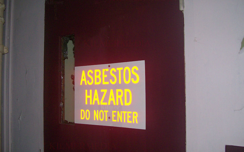ASBESTOS HAZARD warning sign on a door - photo by KilmerMedia