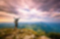 Man at top of mountain with arms stretched and nice sky.jpg