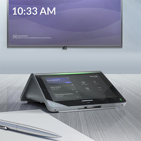 Smart conference room setup with a sleek touchscreen display showing 10:33 AM, and a digital screen on the wall. Silver pen on table.