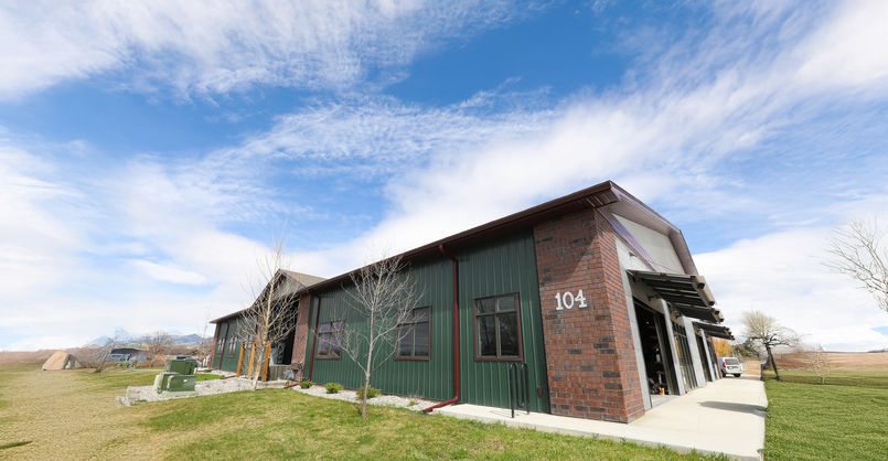 Modern Montana commercial building with brick and green metal siding, viewed from the side under a blue sky