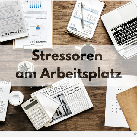 Schreibtisch mit verschiedenen Bürogegenständen wie Laptop, Taschenrechner, Notizbuch, Finanzdokumenten, Zeitung und Kaffeetasse. In der Mitte des Bildes steht groß der Titel: „Stressoren am Arbeitsplatz“. Oben rechts ein Sprechblasen-Symbol, unten rechts der Bildnachweis: © rawpixel via Pixabay.