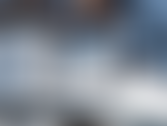 Blank square sign on a modern building exterior, shadowed by tree leaves. Blue sky reflection, sleek design with wood accents.