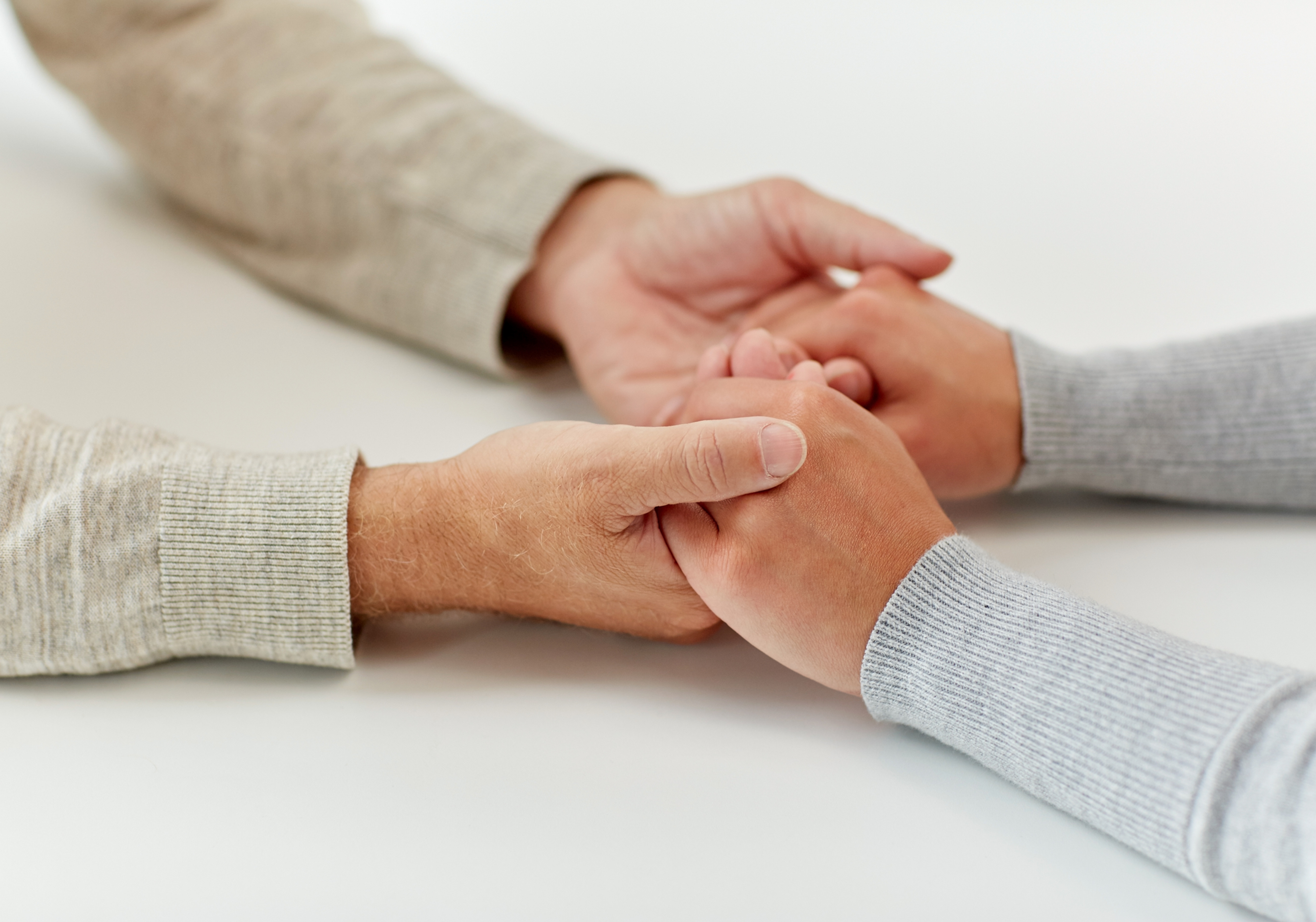 Duas pessoas segurando as mãos em um gesto de apoio e empatia