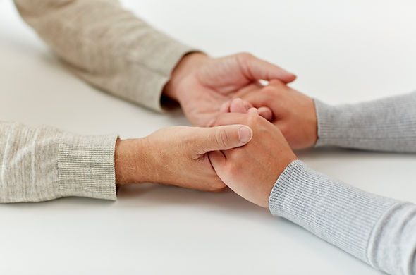 The held hands of a parent and their autistic young adult