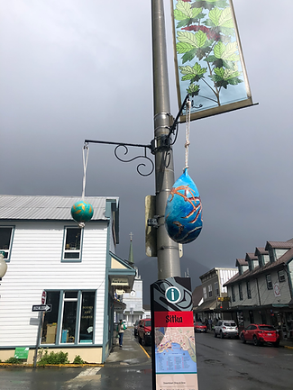 Painted buoys hanging on Lincoln street in Sitka Alaska with a grey sky in the background.