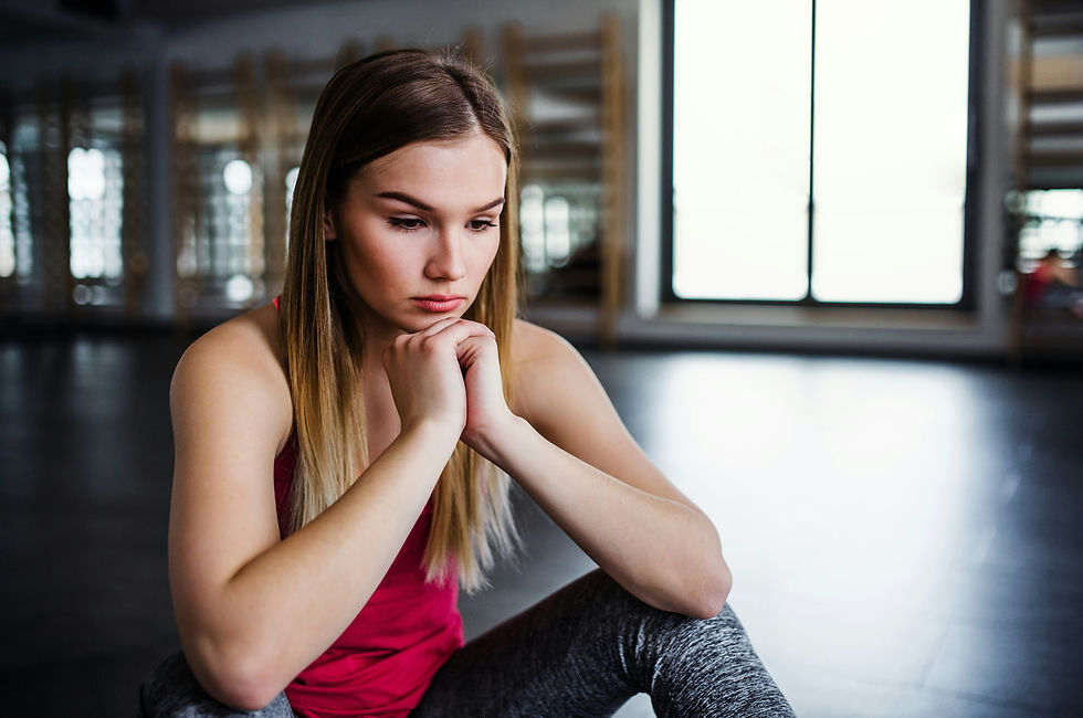 A woman in a pink top sits on the floor, resting her chin on her hands.
