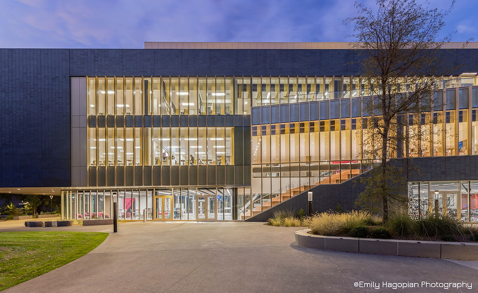 Warm interior light glows through the glass and dark tile facade of the Lindley Center at dusk, photographed by Emily Hagopian Photography.