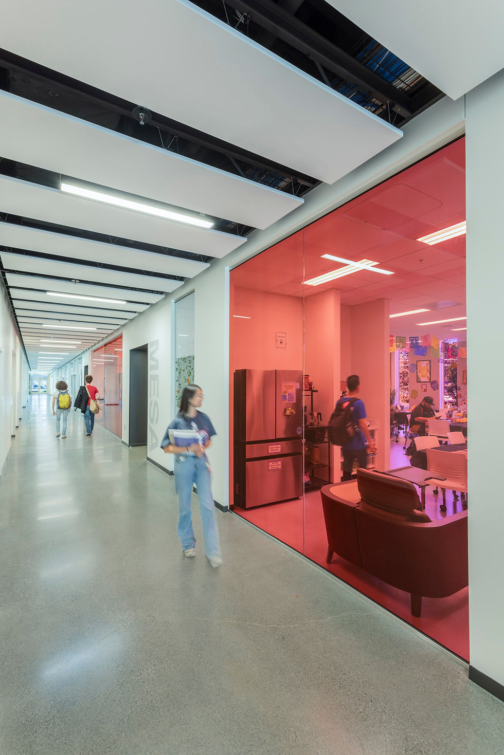 The MESA Center, with its pink walls and tinted glass entry, supports underrepresented students in STEM and has become one of the most popular spaces in the building. The MESA Center. Student walk by in the hallway and are able to see into the space. Lindley Center for STEM Education at the Santa Rosa Junior college. Designed by SmithGroup; Emily Hagopian Photography