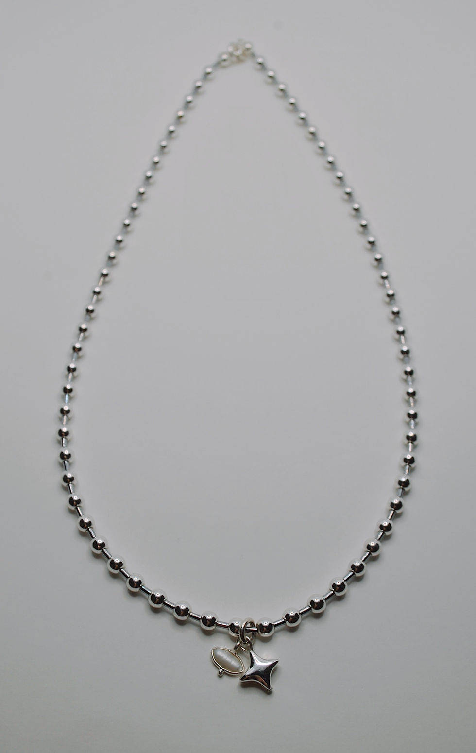 Widok na cały SREBRNY NASZYJNIK Z HEMATYTU LATO RAW STAR wyeksponowany na jasnym tle.