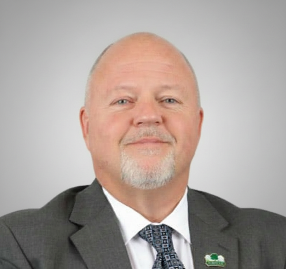 Professional headshot of the Interim President in a suit, centered on a neutral background, portrait orientation.