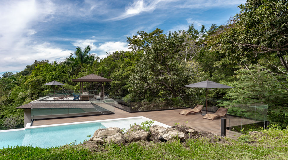 Luxury outdoor pool with lounge chairs, trees, and blue sky background.