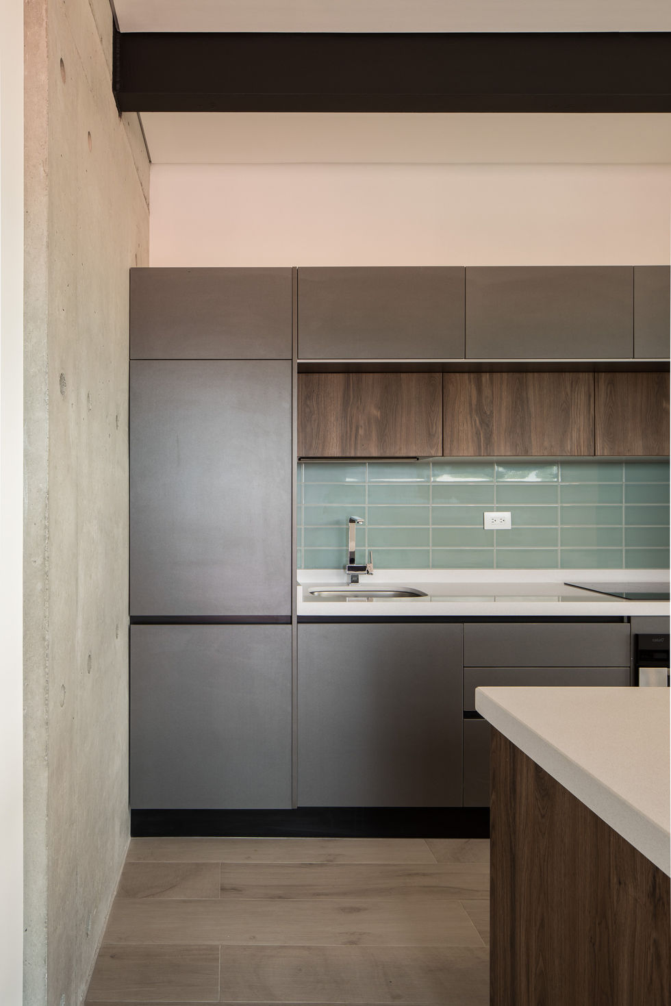 Modern kitchen with gray cabinets, wooden accents, and a light blue backsplash.