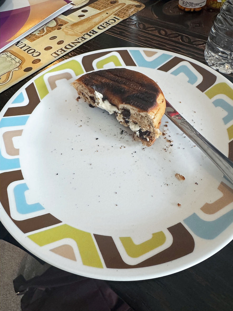 A burnt bagel with cream cheese on a plate, representing unexpected beauty and grace in imperfection.